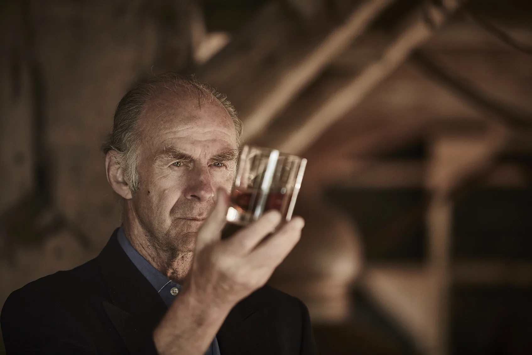 Sir Ranulph Fiennes holding a glass of rum up to the light
